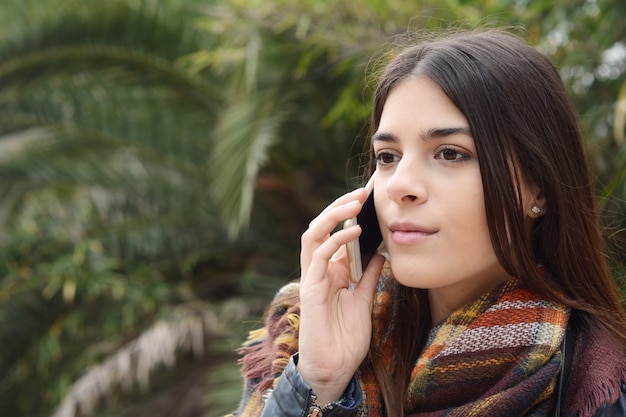 Sluit omhoog van een jonge vrouw die op de telefoon spreekt.