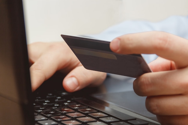 Sluit omhoog van een Mens die online Gebruikend Laptop met Creditcard winkelt