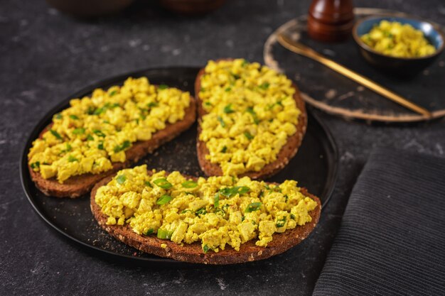 Sluit omhoog van een plaat met de heldere gele sandwiches van de veganistische eiersalade