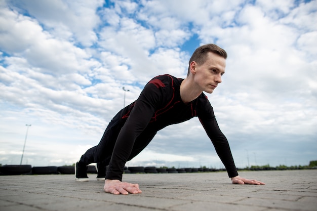 Sluit omhoog van een sterke jonge mensenopdrukoefening op het asfalt van het sportterrein. man training in de ochtend. gezonde levensstijl, sport concept. kopieer ruimte