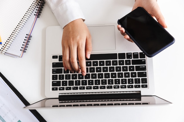 Sluit omhoog van een vrouw in wit overhemd typend op laptop computer