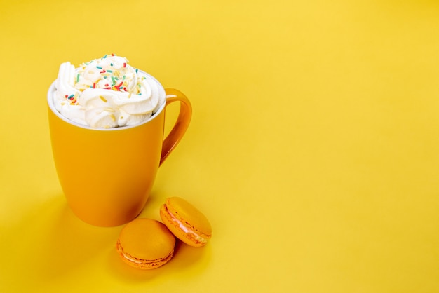 Sluit omhoog van gele koffiekop en Franse makarons op gele achtergrond.