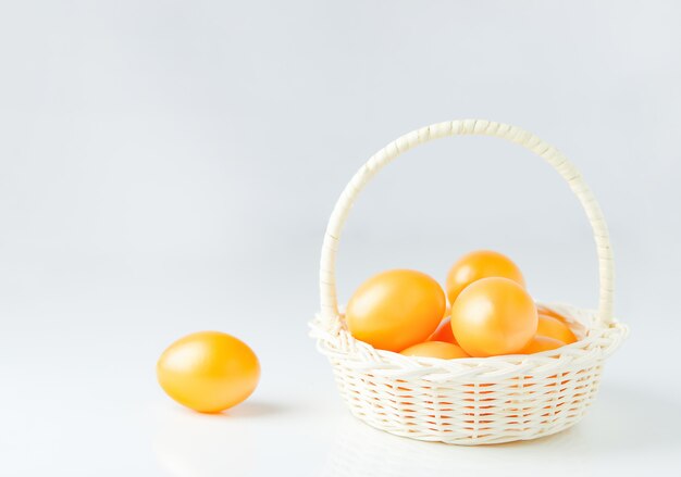 Foto sluit omhoog van gouden paaseieren in witte mand