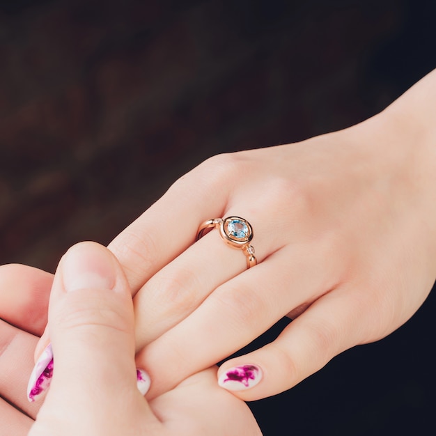 Sluit omhoog van handen van vrouw die de ring met diamant tonen. Ze is verloofd.