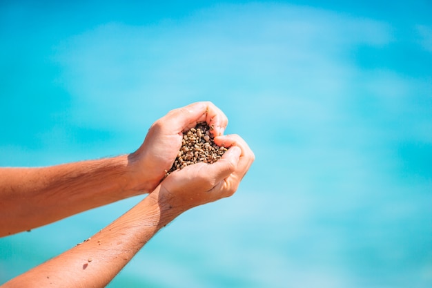 Sluit omhoog van hart dat door mannelijke handenachtergrond de turkooise oceaan wordt gemaakt