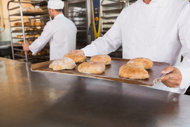 Sluit omhoog van het dienblad van de bakkersholding van brood