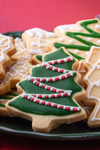 Sluit omhoog van Kerstmis verfraaide suiker cooikes in een plaat op rode lijstachtergrond.