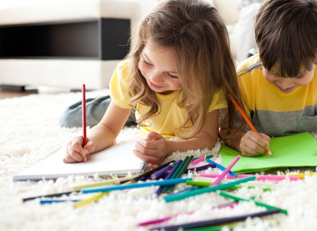 Sluit omhoog van kinderen trekken die op de vloer liggen