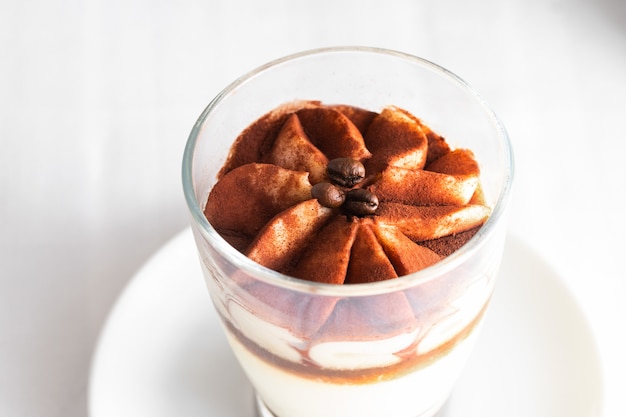 Sluit omhoog van klassieke tiramisu-cake in een glas op concrete achtergrond.