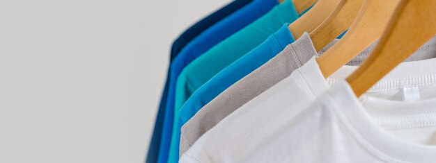 Sluit omhoog van Kleurrijke t-shirts op hangers, kledingsachtergrond