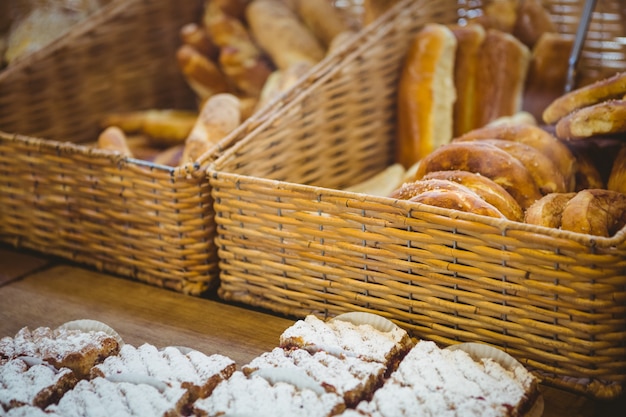 Sluit omhoog van mand met vers brood en gebakje