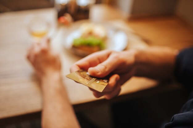 Sluit omhoog van menselijke hand houdend een plastic kaart. Hij stuurt het naar de camera. Guy gaat het eten betalen.