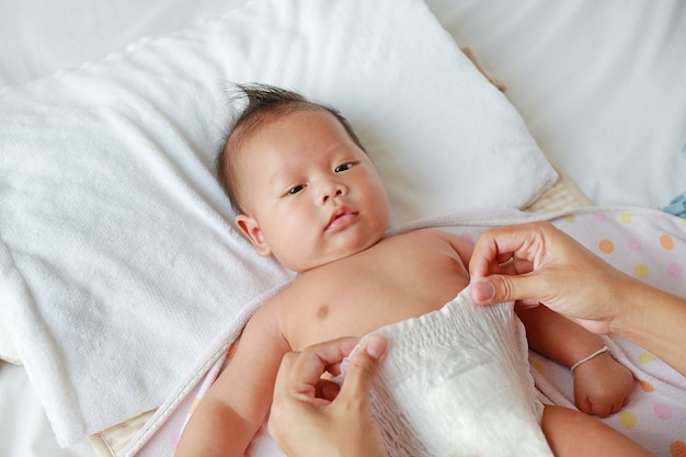 Sluit omhoog van moederhanden gezet op een babyluier aan haar pasgeboren