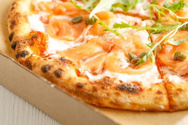 Sluit omhoog van pizza's met verscheidenheid van greens en kaas in karton