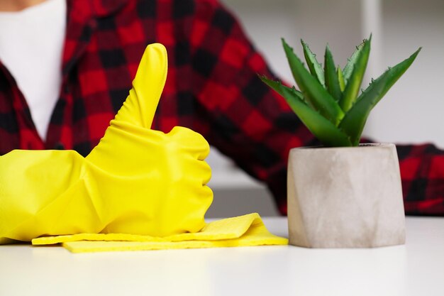 Foto sluit omhoog van reinigingsmachine in gele handschoenen veegt stof in het bureau af