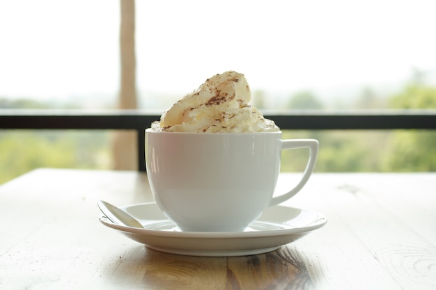 Sluit omhoog van slagroom die met chocolade op hete cacaodrank wordt bedekt.