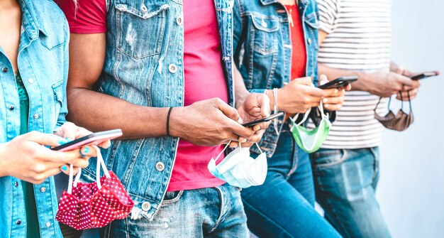 Sluit omhoog van vriendenhanden met gezichtsmaskers gebruikend het volgen app op mobiele smartphones