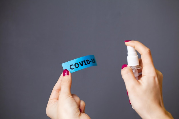 Sluit omhoog van vrouw die antiseptisch op coronavirusinschrijving bespuiten