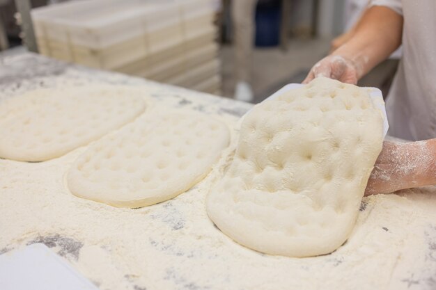 Sluit omhoog van vrouw die Pizzadeeg kneden.