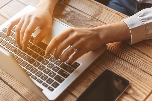 Sluit omhoog van vrouw het typen op laptop in koffiewinkel