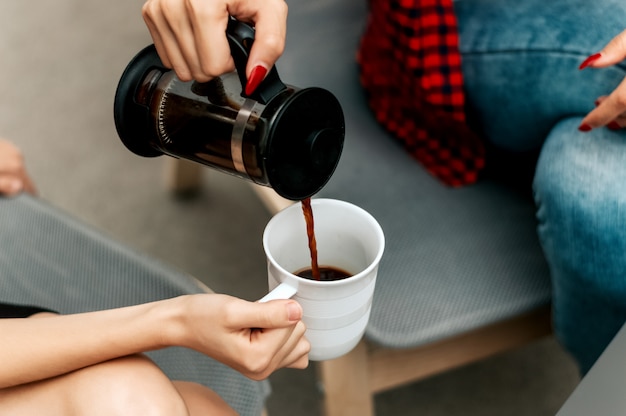 Sluit omhoog van vrouwen gietende koffie in kop.