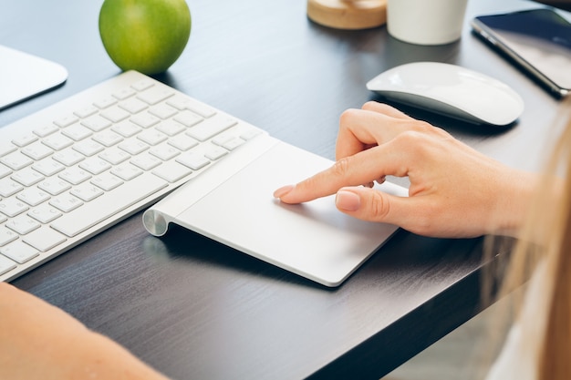 Sluit omhoog van vrouwenhand wat betreft op laptop het stootkussen van de computermuis