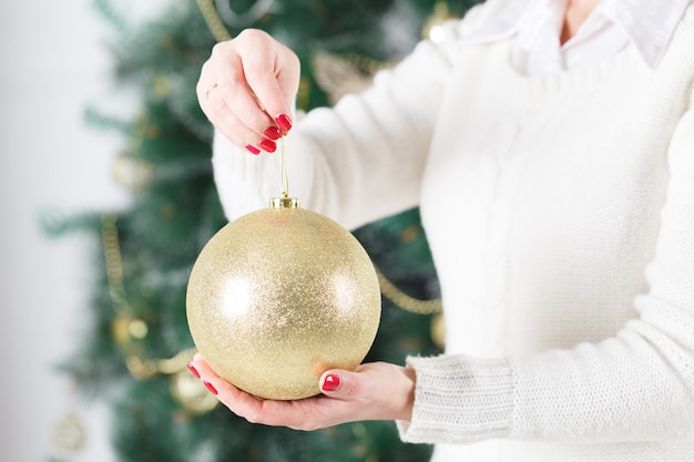 Sluit omhoog van vrouwenhanden houdend Kerstmis goold bal. Decoratie, vakantie en mensen concept