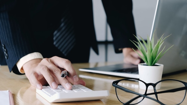 Sluit omhoog van zakenman of accountant de pen die van de handholding aan calculator werkt om bedrijfsgegevens te berekenen