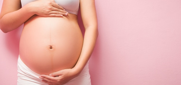 Foto sluit omhoog van zwangere buik op roze achtergrond