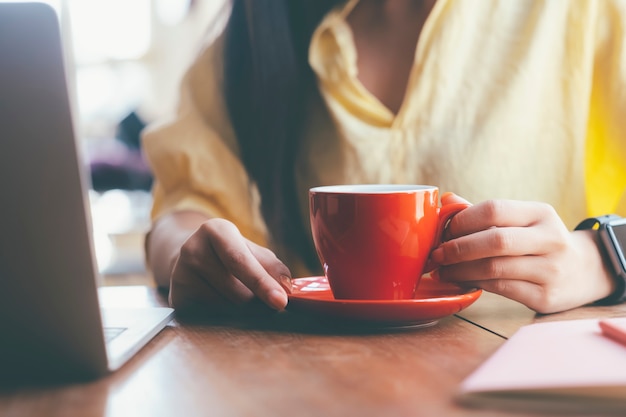 Sluit omhoog vrouw die een rode kop van koffie houdt