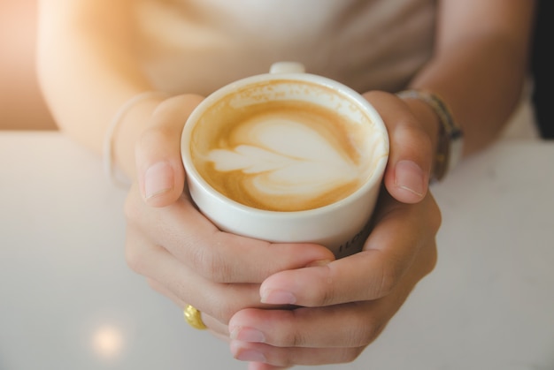 Sluit omhoog vrouwelijke hand houdend witte koffiekop