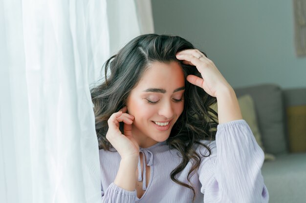 Sluit portret van een jonge mooie krullende vrouw in een lila jurk