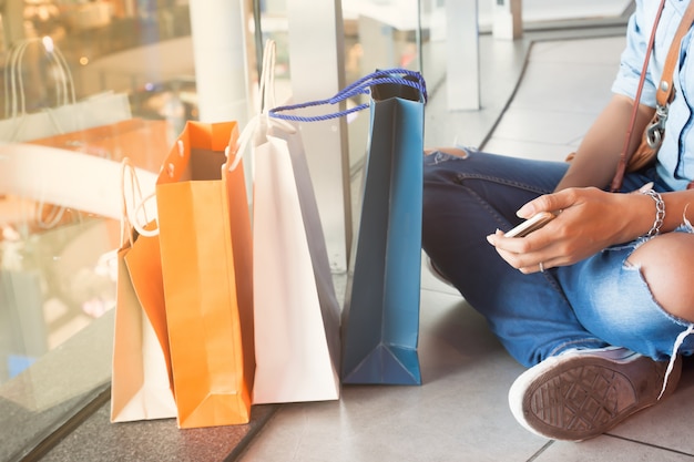 Sluit smartphone van de de handholding van de vrouw omhoog met het winkelen zakken