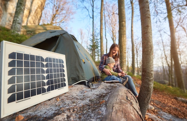 Sluit zonnebatterij op de camping op zonnige herfstdag af tegen de achtergrond van een jong gezin