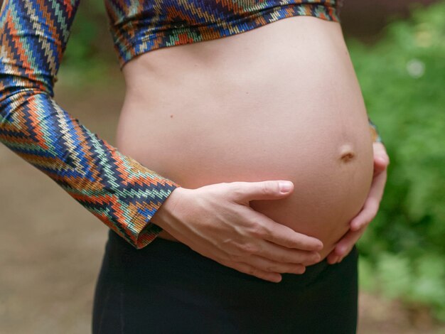 Sluiten van zwangere moderne jonge vrouw haar buik buitenshuis aan te raken.