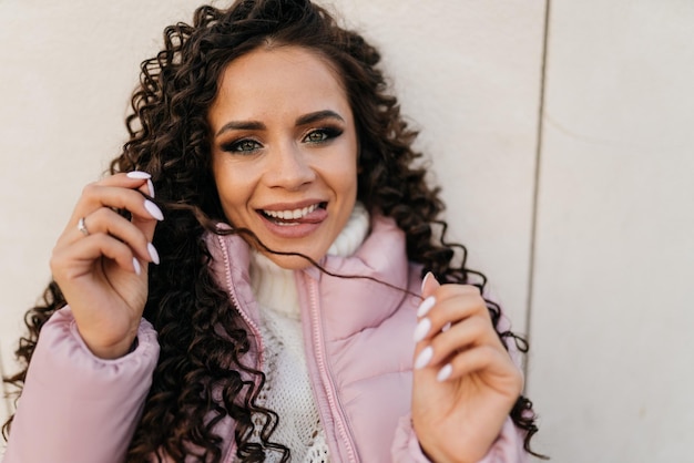 Slyly glimlachen en tonen van de tong poseren krullend brunette close-up