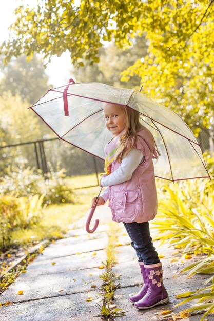Photo slyly smiling girl posing under umbrella in park