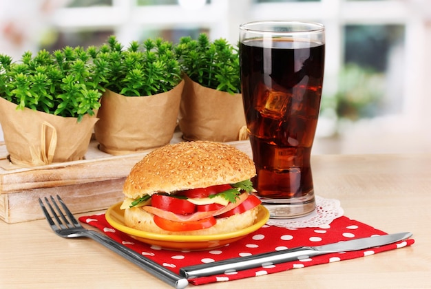 Foto smakelijk broodje op kleurenplaat op houten tafel op vensterachtergrond