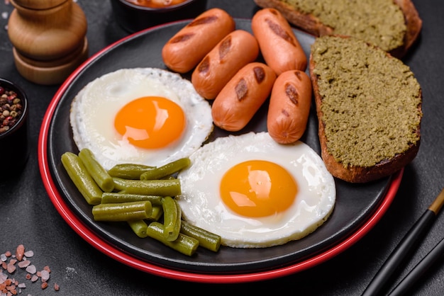 Smakelijk Engels ontbijt van gebakken eieren, bonen, asperges, worstjes met specerijen en kruiden