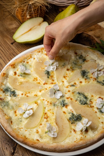 Smakelijk gebakken pizza met witte saus, peer en gorgonzola kaas op een houten tafel. bovenaanzicht