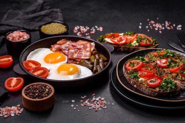 Smakelijk ontbijt bestaat uit eieren, spek, bonen, tomaten met specerijen en kruiden