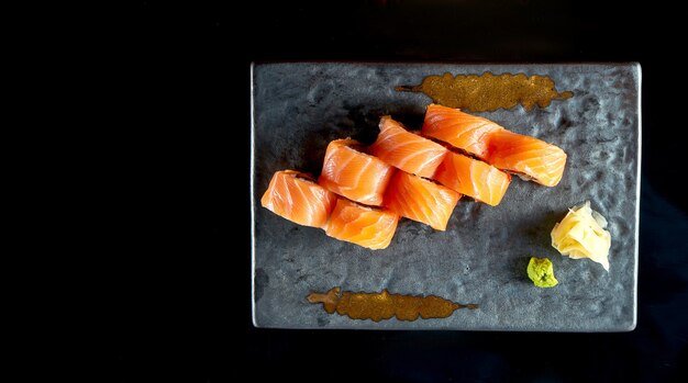 Foto smakelijk sushi roll met zalm, paling, avocado en tobiko kaviaar, geserveerd op een keramische plaat met gember en wasabi.