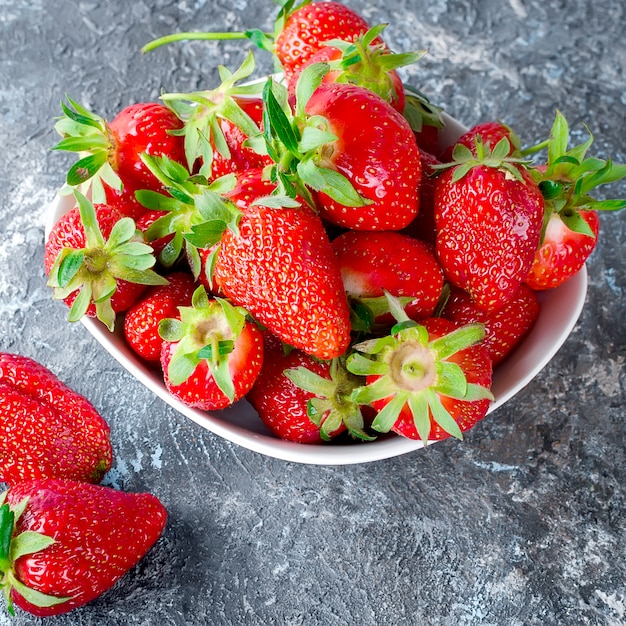 Smakelijke aardbei in de kom op een grijze achtergrond.