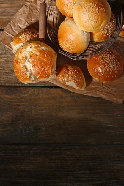 Smakelijke broodjes met sesam in mand op houten achtergrond