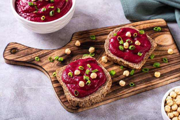 Smakelijke bruschetta's van roggebrood met bietenhummus en bieslook op een snijplank