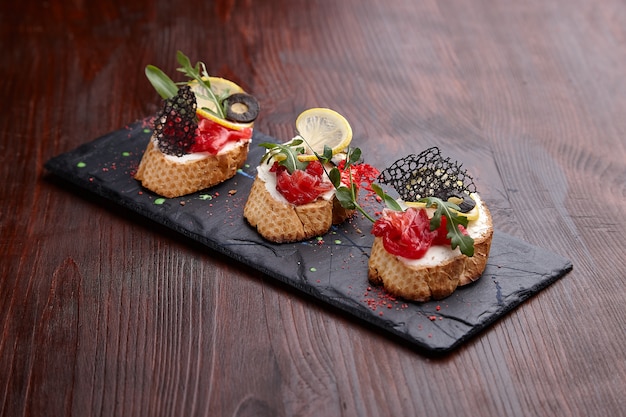 Smakelijke bruschettas op een stenen standaard op een houten tafel