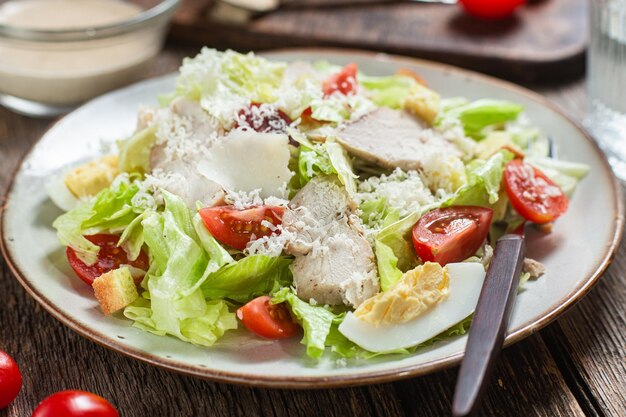 Foto smakelijke caesarsalade in een bord op een houten tafel