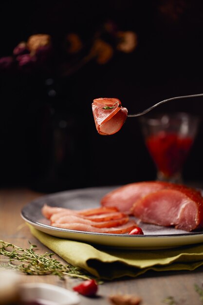 Smakelijke carpaccio-plak die op een vork op donkere achtergrond wordt verpakt.