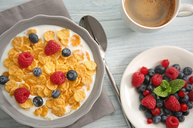 Smakelijke cornflakes met frambozen en bosbessen op grijze houten ondergrond