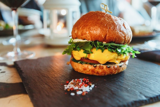 Smakelijke dikke dubbele Amerikaanse burger met varkens- en rundvlees vleesbrander kaas en saus Twee stukjes brood geserveerd op zwarte plaat in restaurant Amerikaanse fastfoodlunch